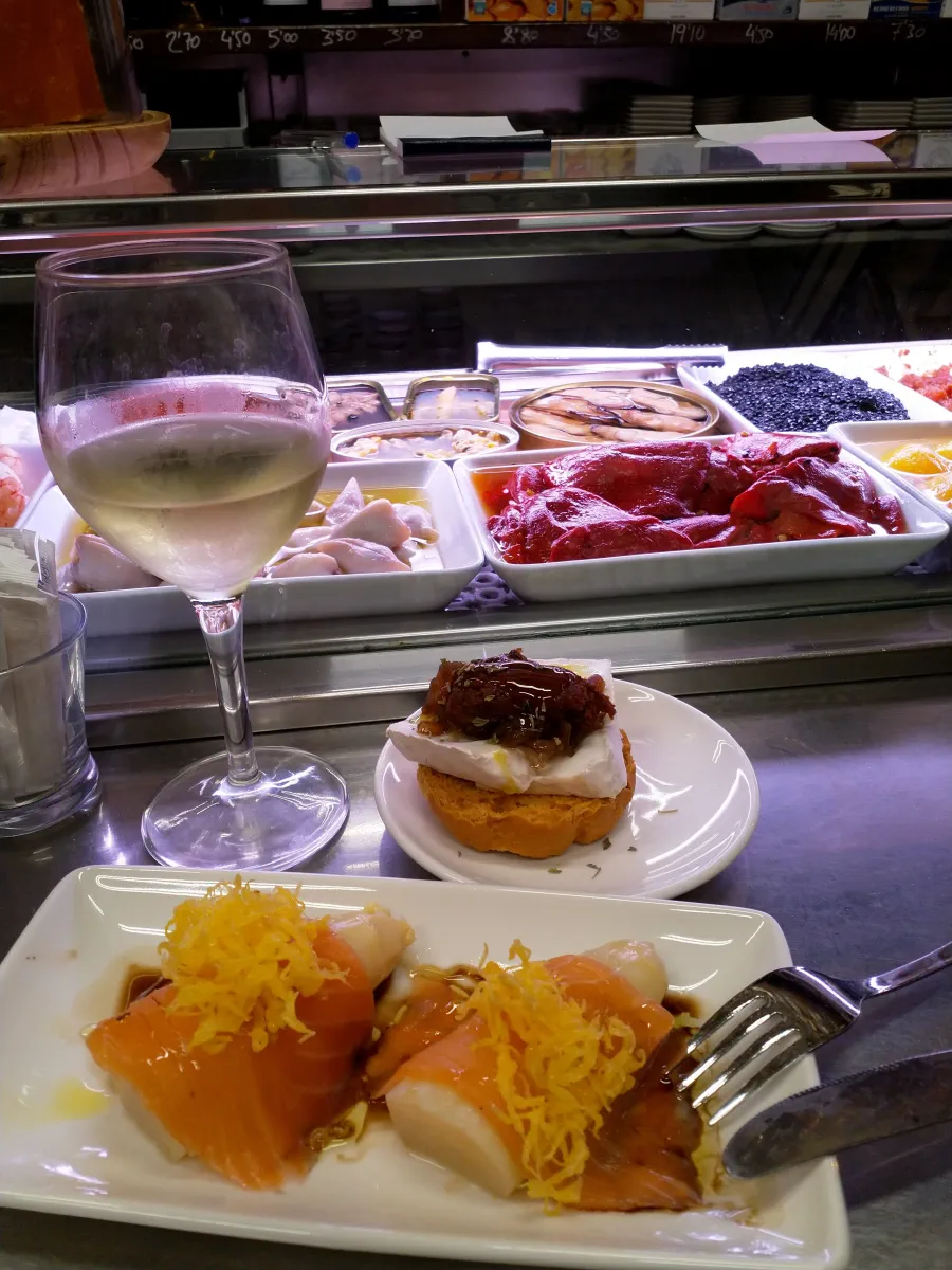 a glass of white wine and various delicious spanish tapas